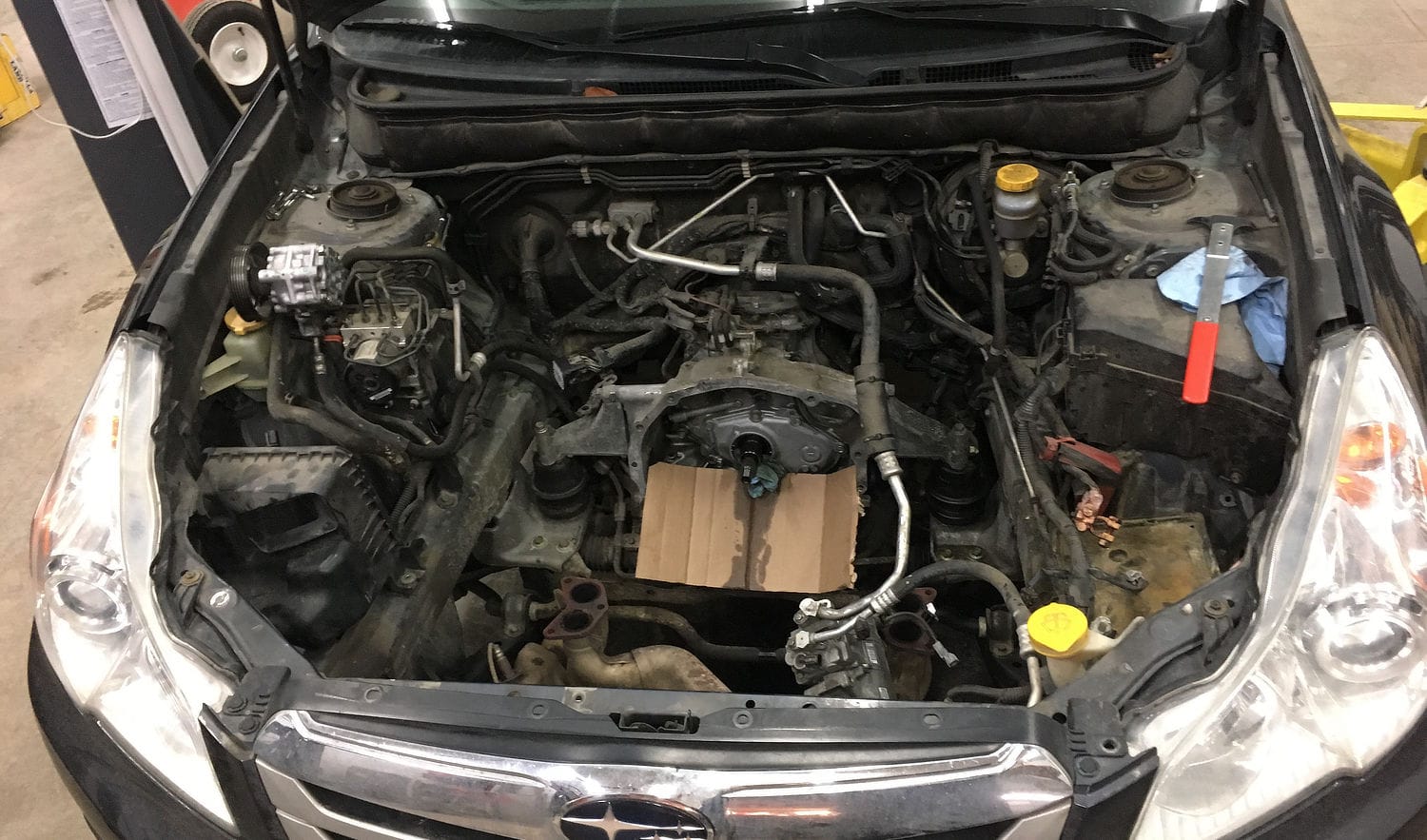 Subaru engine bay with the engine removed, exposing the transmission for torque-converter replacement